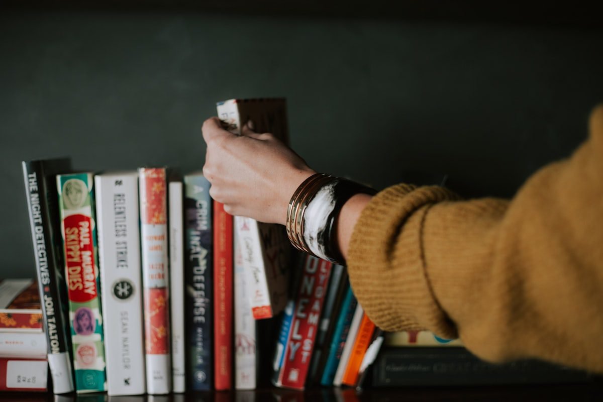 Person selecting a book from a shelf — improving focus and memory