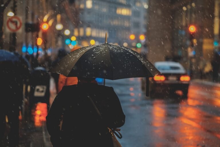 Person with an umbrella on a rainy city street during monsoon in Bangladesh