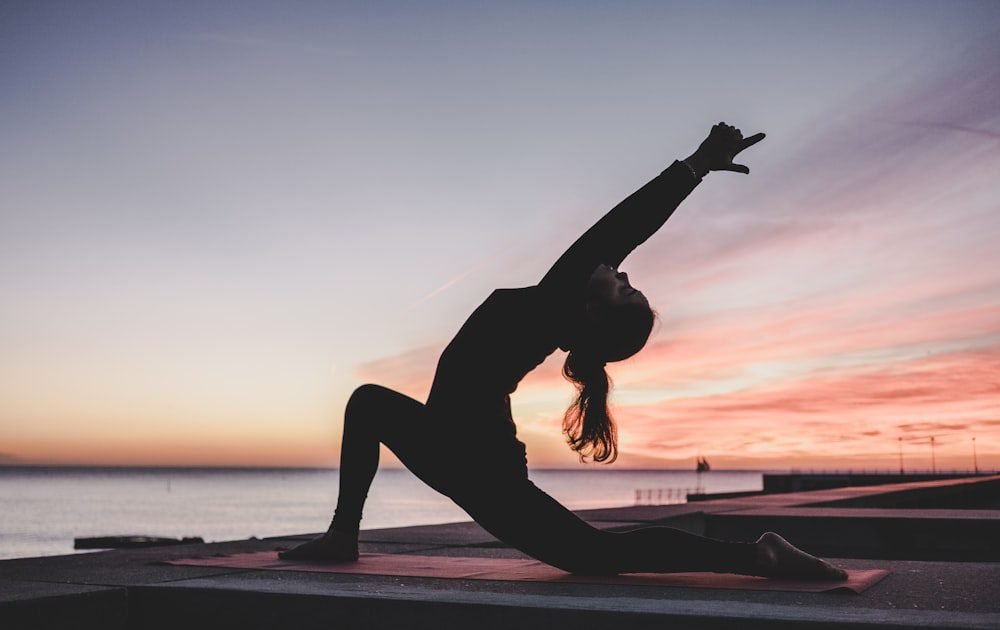 Person stretching in a yoga pose at sunset — flexibility and mobility